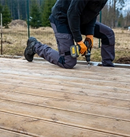 Contractor building wood deck with power drill